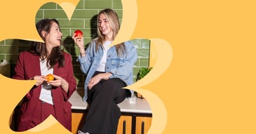 Twee collega's lachen en eten fruit samen tijdens een werkpauze, betrokken personeel zorgt voor meer werkgeluk