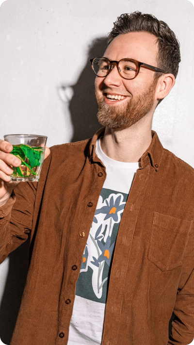 Lachende man proost met muntthee van werkfruit van, onderdeel van Froot’s missie voor vitaliteit op kantoor.