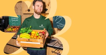 Fruitbezorger van Froot levert een houten krat vol vers fruit op kantoor, als symbool voor gezonde en vitale werkplekken.